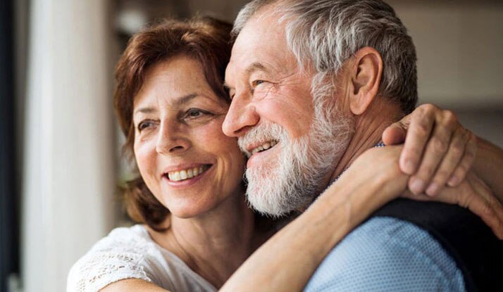 Um Casal senior em casa olhando pela janela