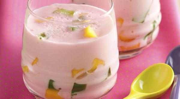 fotografia em tons de cinza e rosa de uma bancada cinza vista de frente, contém um pano rosa com dois copos transparentes e ambos contém a bebida com pedaços de frutas