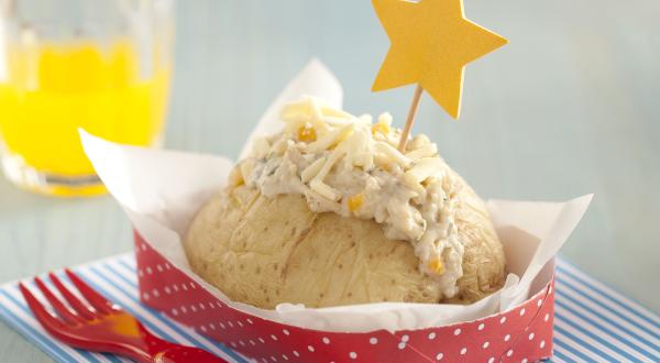 foto em tons de azul, branco e vermelho tirada de um pano listrado em tons de azul e branco. Contém um recipiente vermelho com bolinhas brancas com uma batata e creme de frango por cima e ao lado um garfo para servir