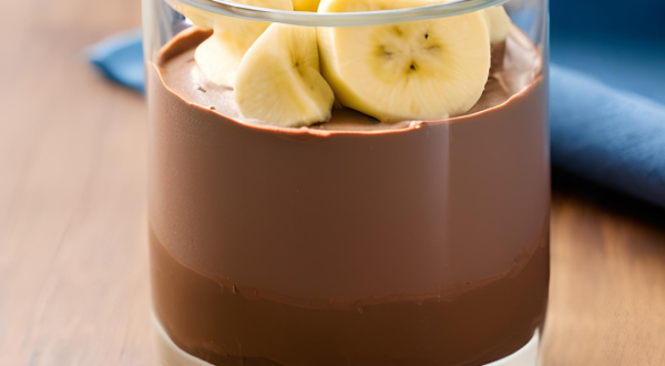 Foto da Receita de Mousse Chocolate com Banana. Observa-se um copo com o mousse dentro e bananas decorando o topo. Imagem ilustrativa gerada por inteligência artificial.